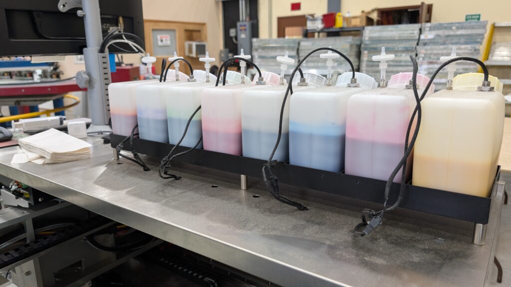 BombyxJet printer ink bottles arranged on top of the machine in a production shop.